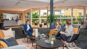 A modern hotel lobby with glass walls, comfortable seating, and a reception area. - Lakeside Hotel and Conference Centre (Macquarie Park)
