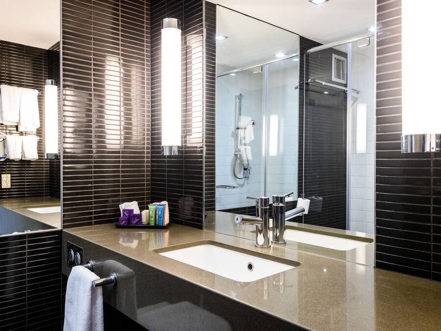 A modern bathroom with a large mirror, a sink, and a glass shower enclosure.