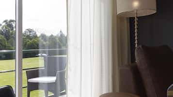 A room with a large window, a sofa, a table, and a lamp.