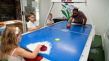 A table tennis table with a digital scoreboard, surrounded by children and an adult.