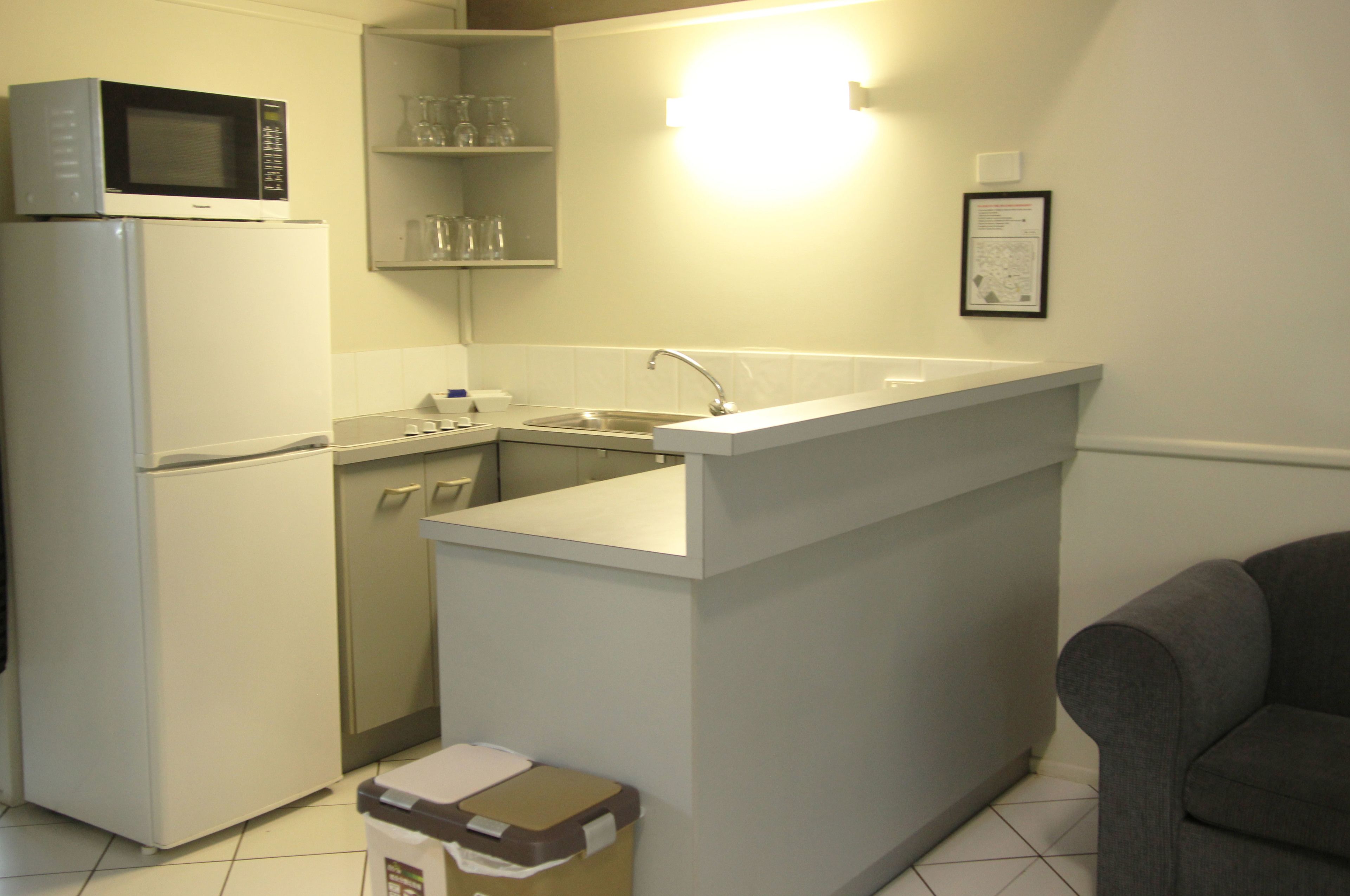 Una cocina compacta con refrigerador, microondas, pileta y una pequeña mesada.