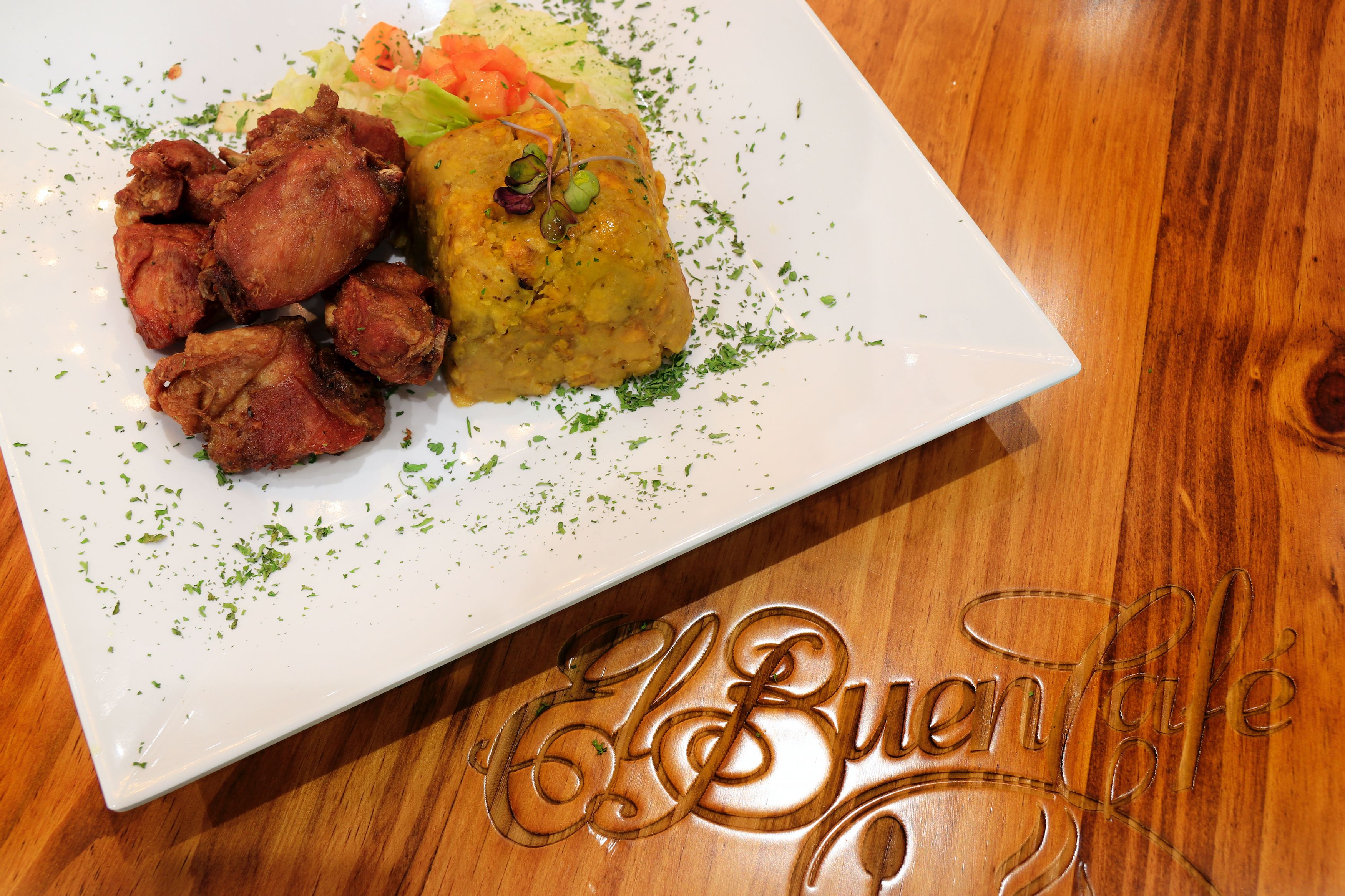 Une assiette de nourriture comprenant du poulet frit et un plat jaune, qui pourrait être un type de riz ou de curry, le tout servi sur une assiette blanche.