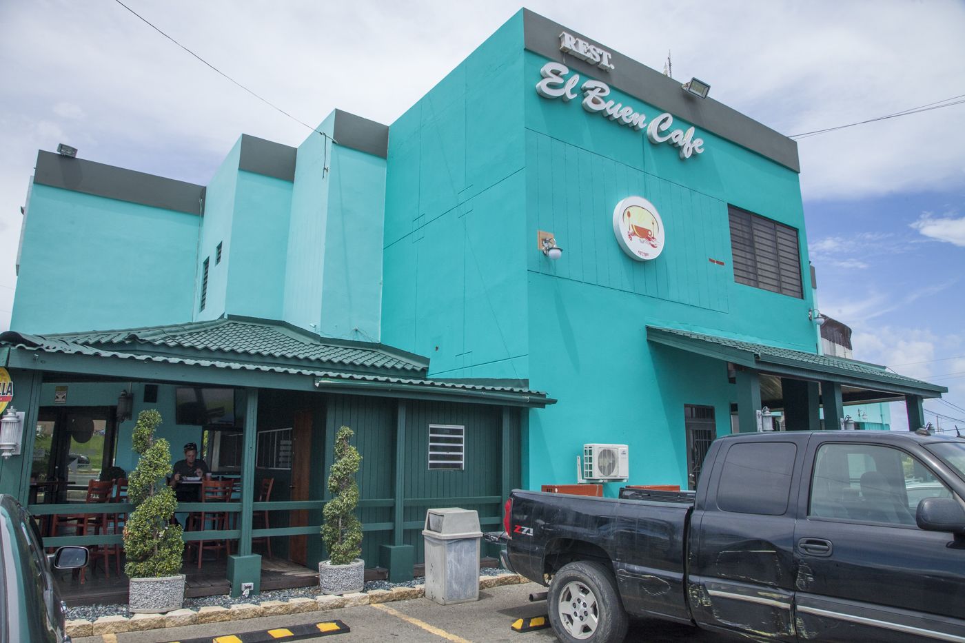 Un edificio turquesa con un letrero que dice 'El Buen Cafe'.