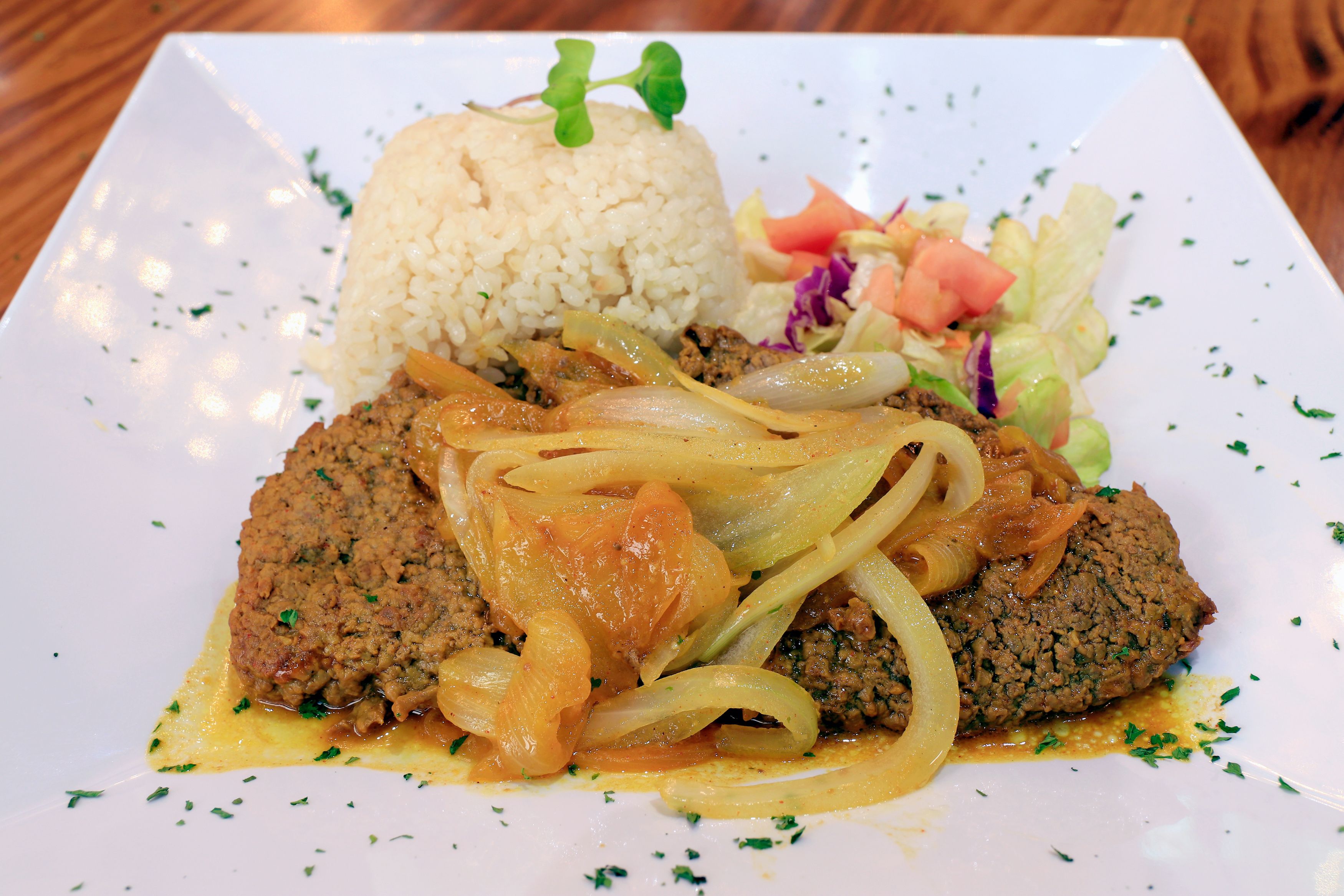 A plate with a meat dish, rice, and a side salad.