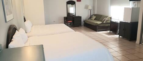 A hotel room with two beds, a desk, a chair, a TV, and a wardrobe.