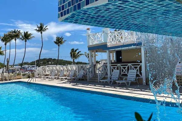 Una piscina al aire libre, sombrillas, sillones reclinables de piscina
