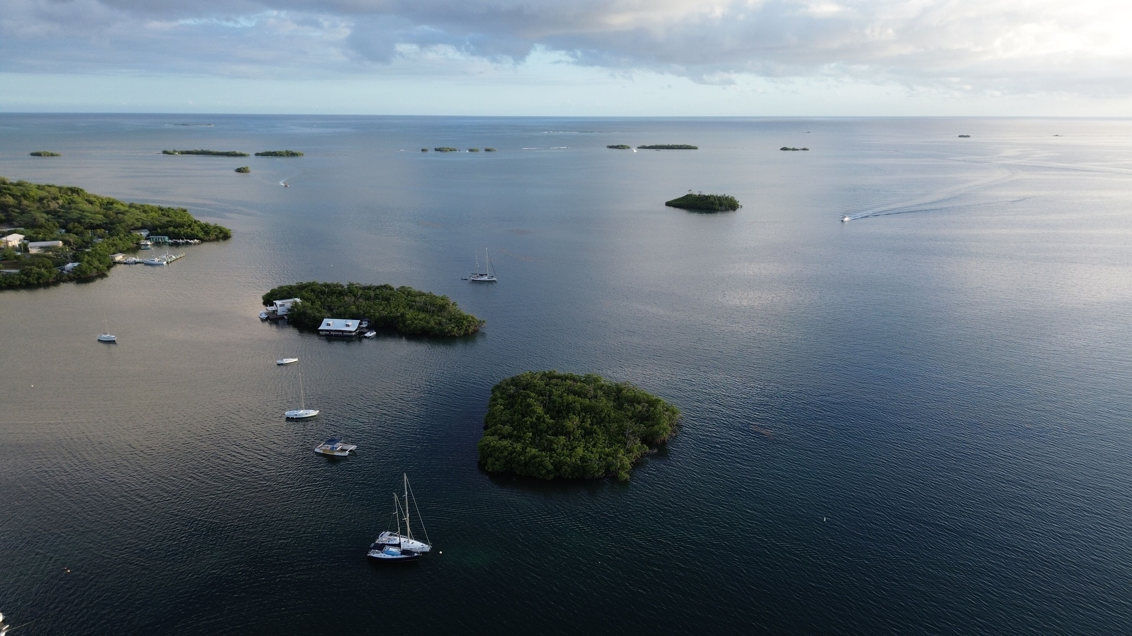 Vista aérea de una zona costera con varias islas pequeñas, barcos y un puerto deportivo.