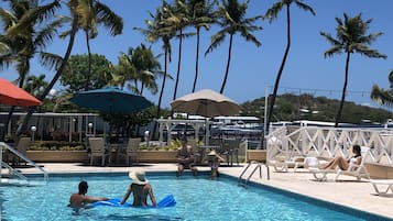 Una piscina al aire libre, sombrillas, sillones reclinables de piscina