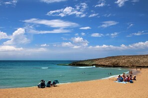 Na praia, espreguiçadeiras, guarda-sóis, toalhas de praia 