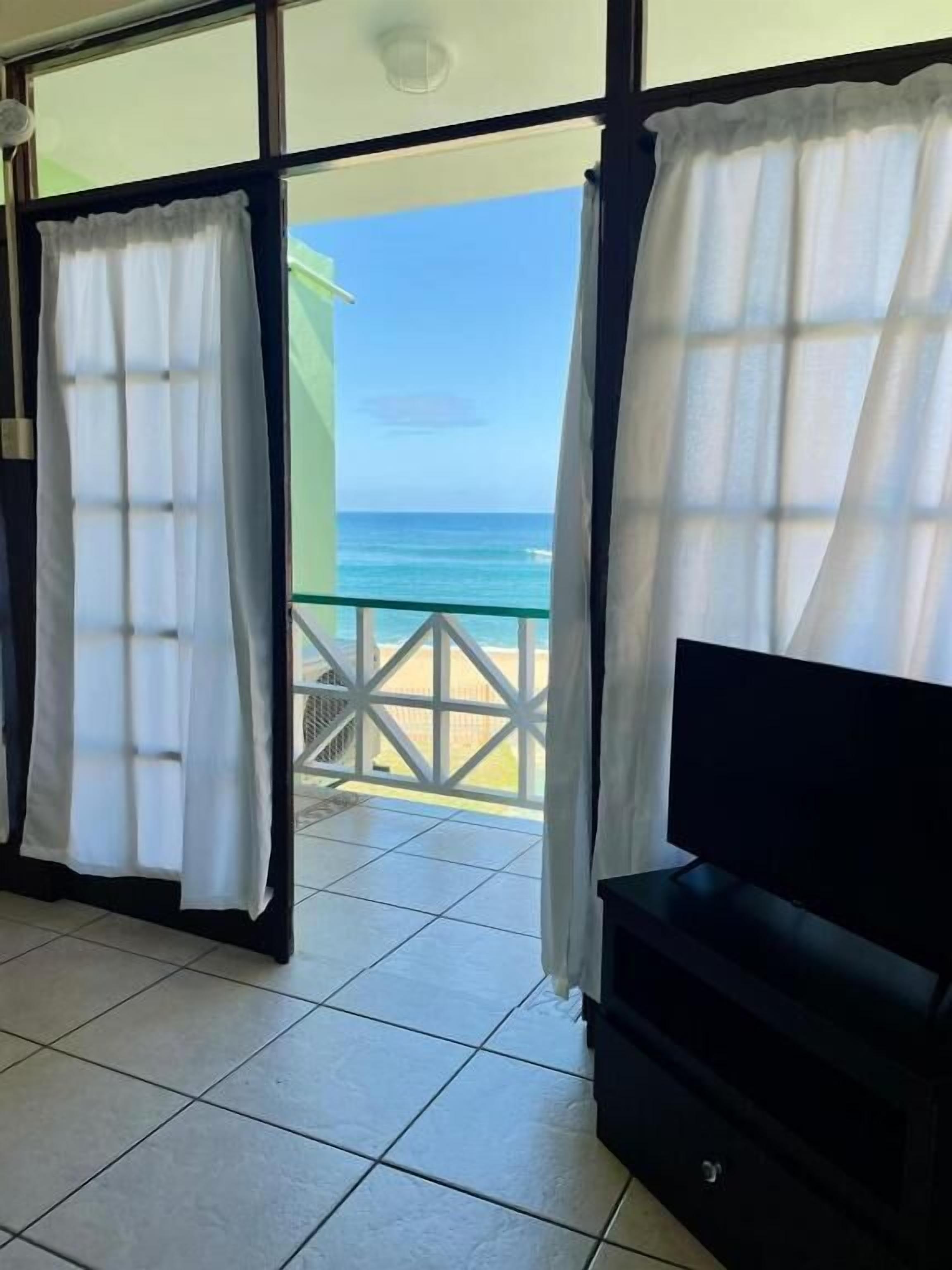 A room with a view of the ocean, a TV, and a tiled floor.