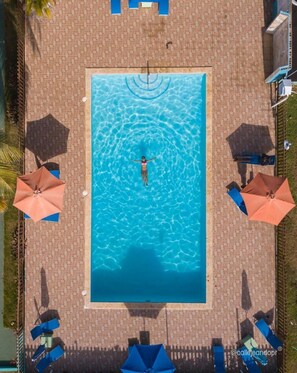 Una piscina al aire libre, sombrillas, sillones reclinables de piscina