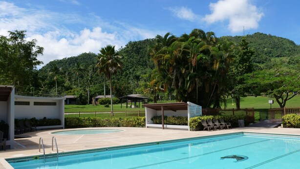 Una piscina con dos zonas de descanso y vistas a una colina verde exuberante.