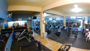A gym with various exercise equipment, including dumbbells, weight machines, and cardio machines.