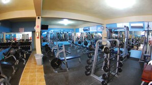 Un gimnasio con diversos equipos de ejercicio, entre ellos máquinas de pesas y pesas libres.