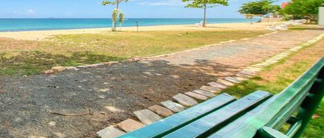 A park with a paved path, green benches, and trees.
