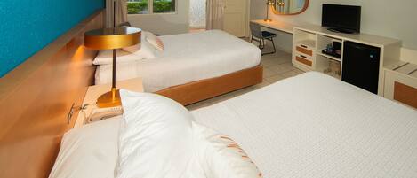 A hotel room with two beds, a desk with a computer, a television, and a minibar.