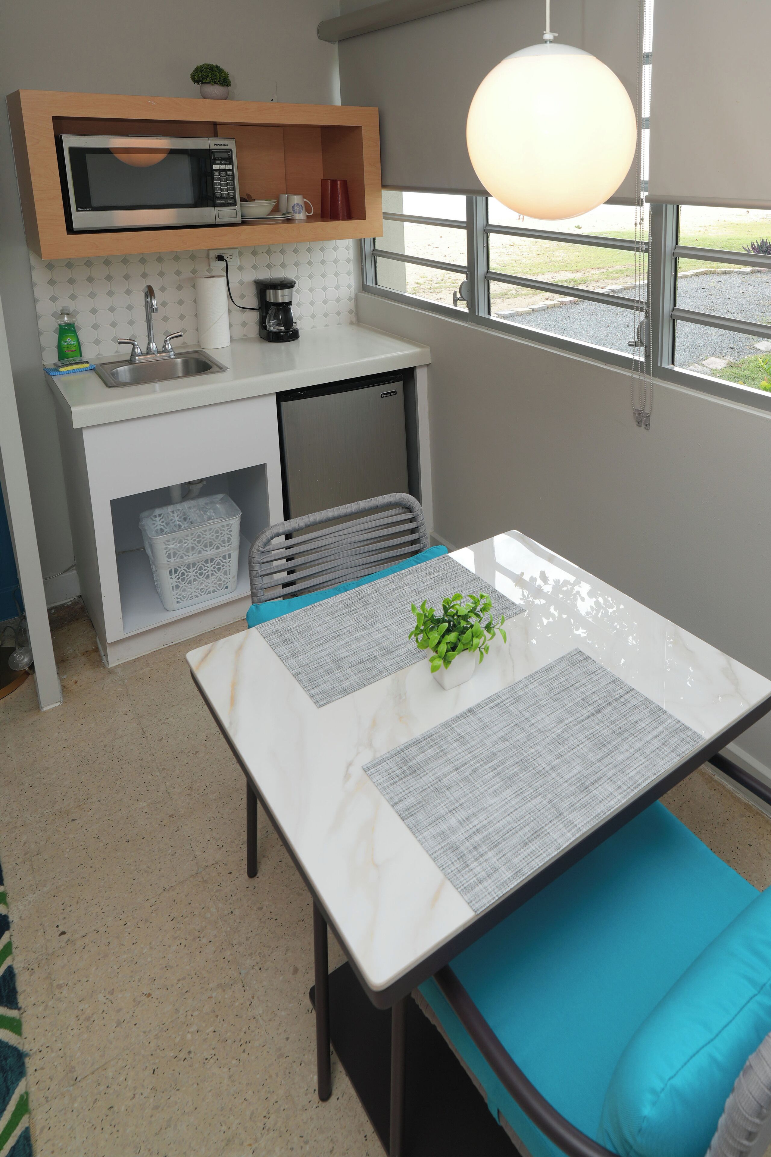 A compact kitchen with a microwave, coffee maker, and sink.