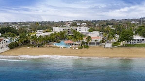 A beachfront hotel with a swimming pool, palm trees, and a view of the ocean. - Rincon of the Seas - Grand Caribbean Hotel (Rincon)