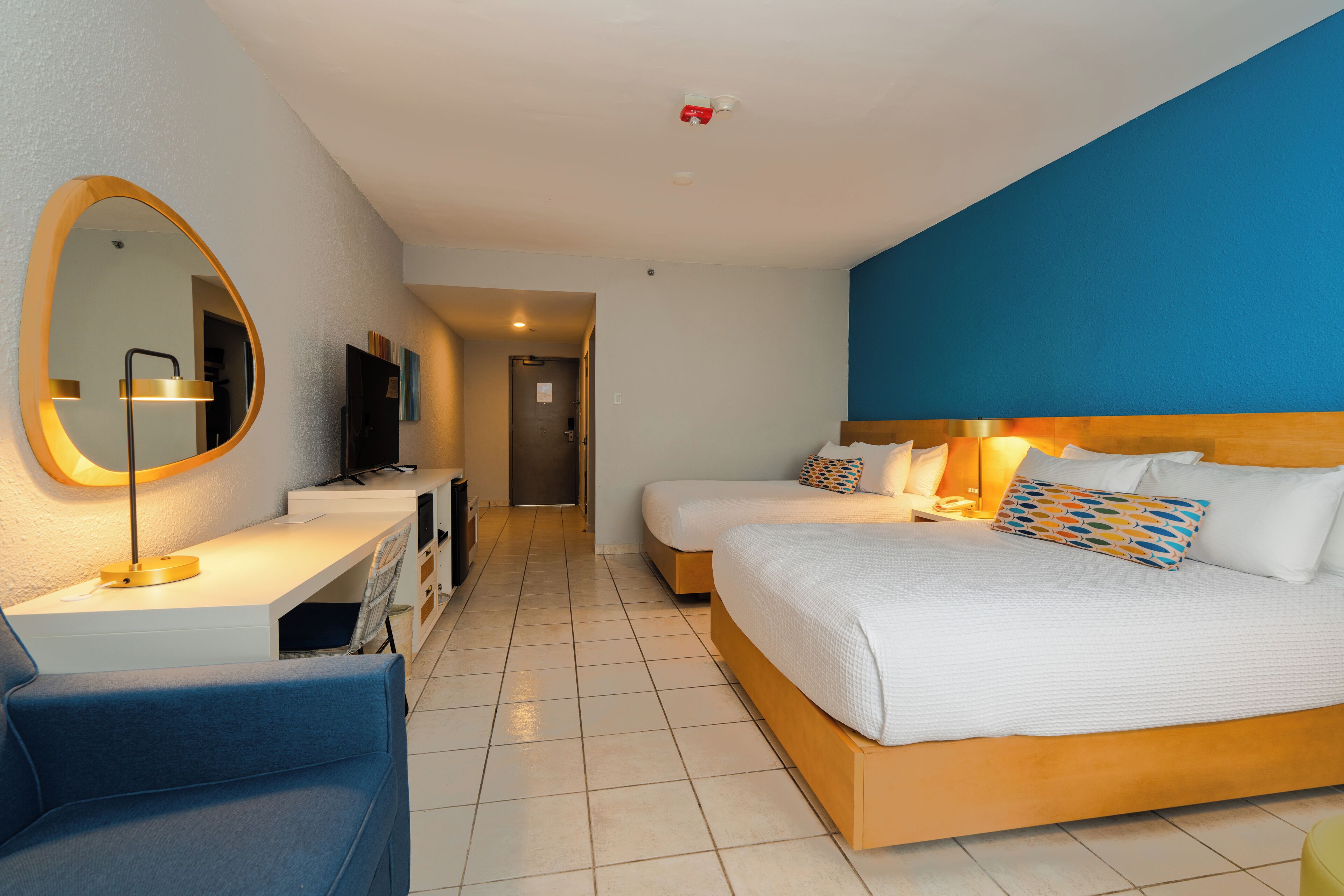Una habitación de hotel moderna con una cama grande, un escritorio con computadora, una silla y un televisor.