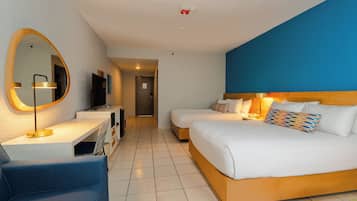 Una habitación de hotel moderna con una cama grande, un escritorio con computadora, una silla y un televisor.