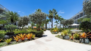 A pathway leading to a building with multiple floors, surrounded by well-maintained greenery and palm trees. - Rincon of the Seas - Grand Caribbean Hotel (Rincon)