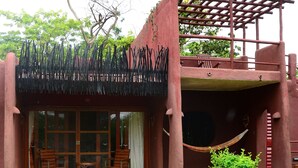 A rustic building with a covered porch, a hammock, and a small garden area. - Amboseli Serena Safari Lodge (Amboseli)