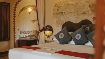 Een hotelkamer met een bed, nachtkastje, lamp en een muurschildering.