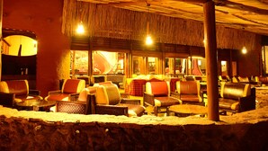 Een buitenzitgedeelte met rieten dak, leren stoelen en tafels.