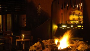 A cozy room with a fireplace, wooden furniture, and a bar area with bottles. - Amboseli Serena Safari Lodge (Amboseli)