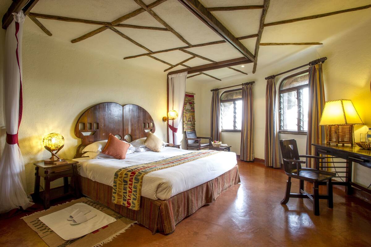 A traditional room with a wooden bed, a desk with a lamp, and a chair.