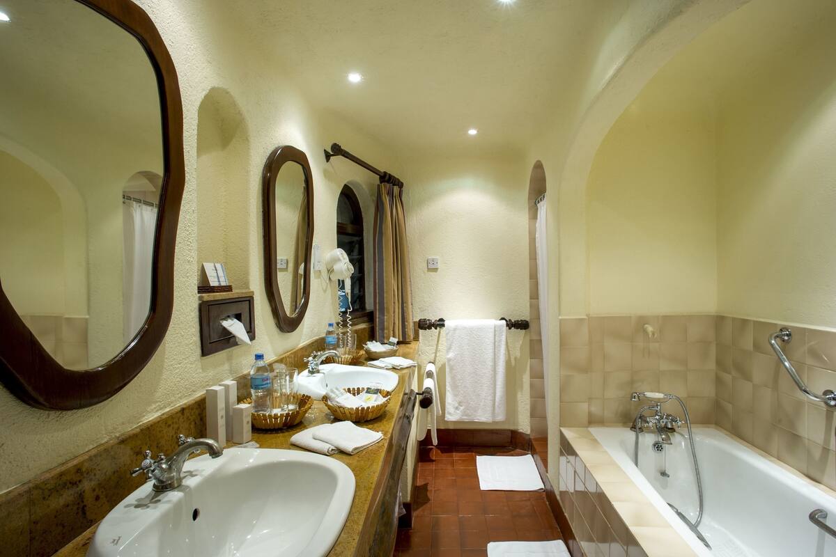 A bathroom with two sinks, a bathtub, and a shower.