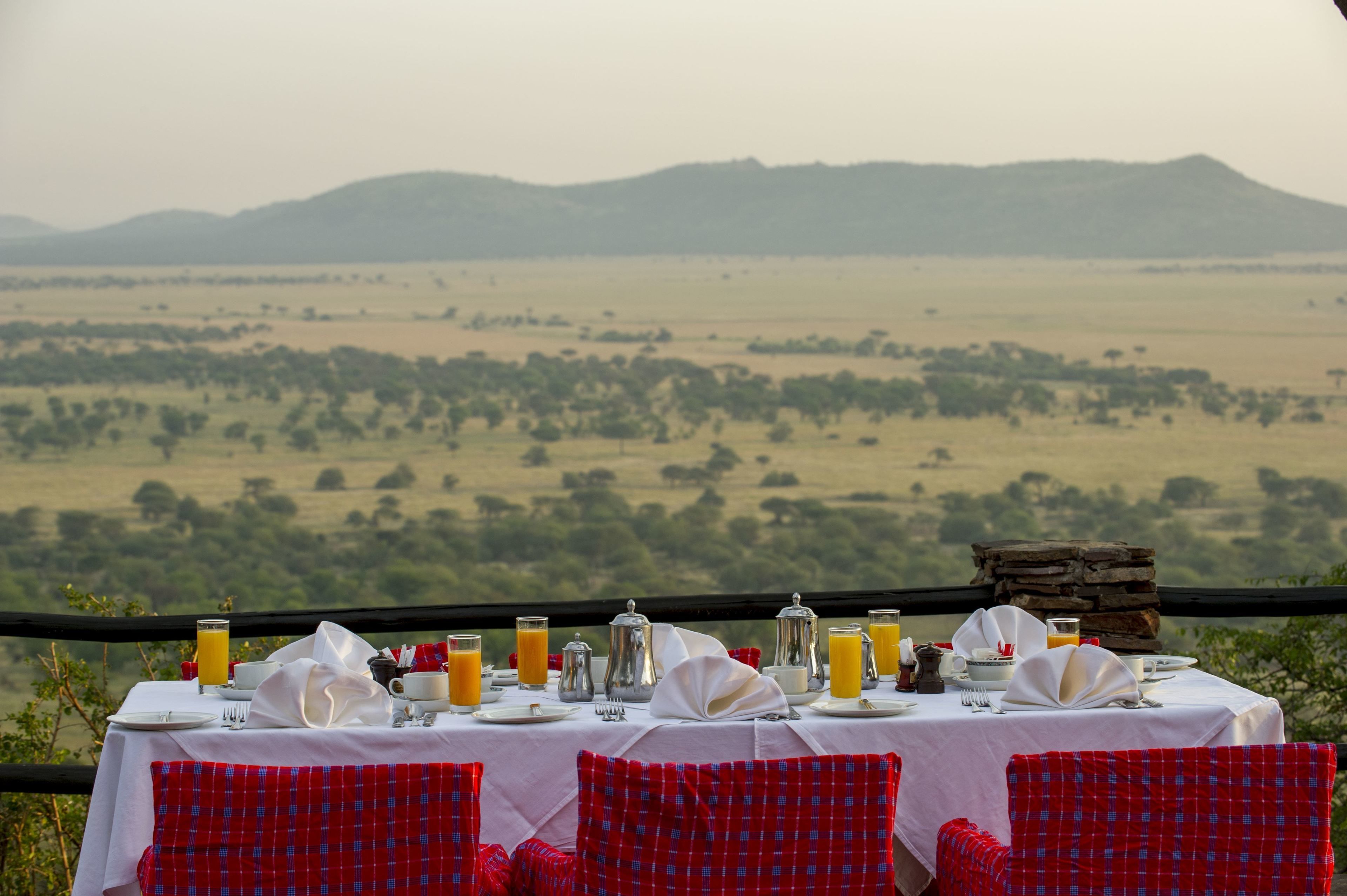A table set for breakfast with a view of a vast landscape.
