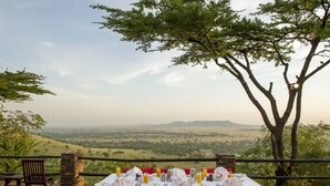A table set for two with a view of a valley and mountains in the background.