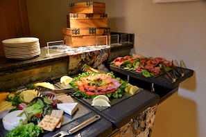 Un buffet proposant une variété de plats, notamment des salades, des viandes, des fromages et des pains.