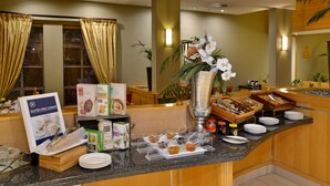 Zona de bufé con diversas opciones de comida, que incluyen alternativas sin gluten y selección de té blanco, además de una estación de café.