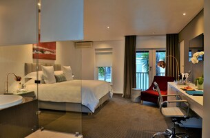 A hotel room with a bed, a desk, a chair, a bathroom, and a large window.
