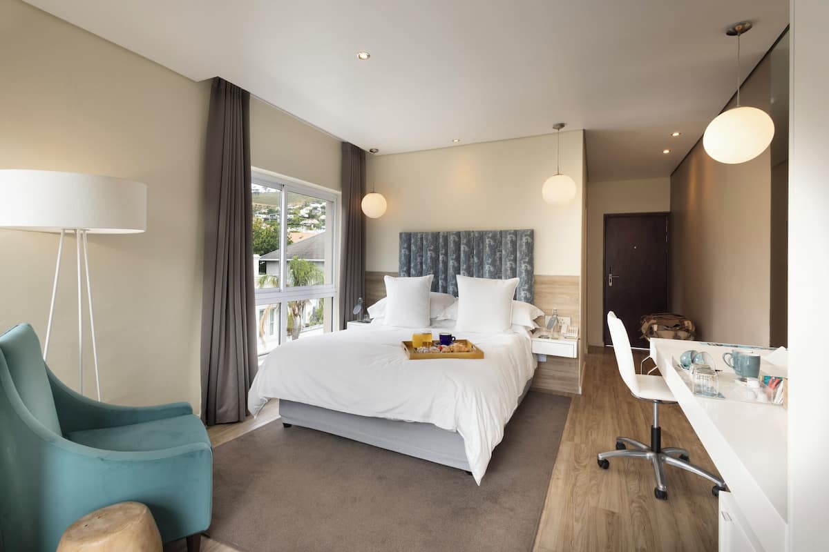 A modern hotel room with a large bed, a desk, and a chair.