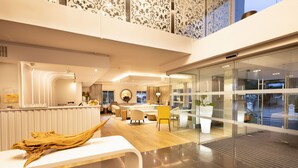 Un hall d’hôtel moderne comprenant un comptoir d’accueil, un espace salon et une cloison en verre.