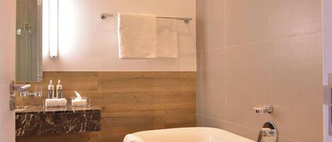 Une salle de bain moderne avec une baignoire sur pieds, un lambris en bois, un plan de toilette en marbre et un grand miroir.