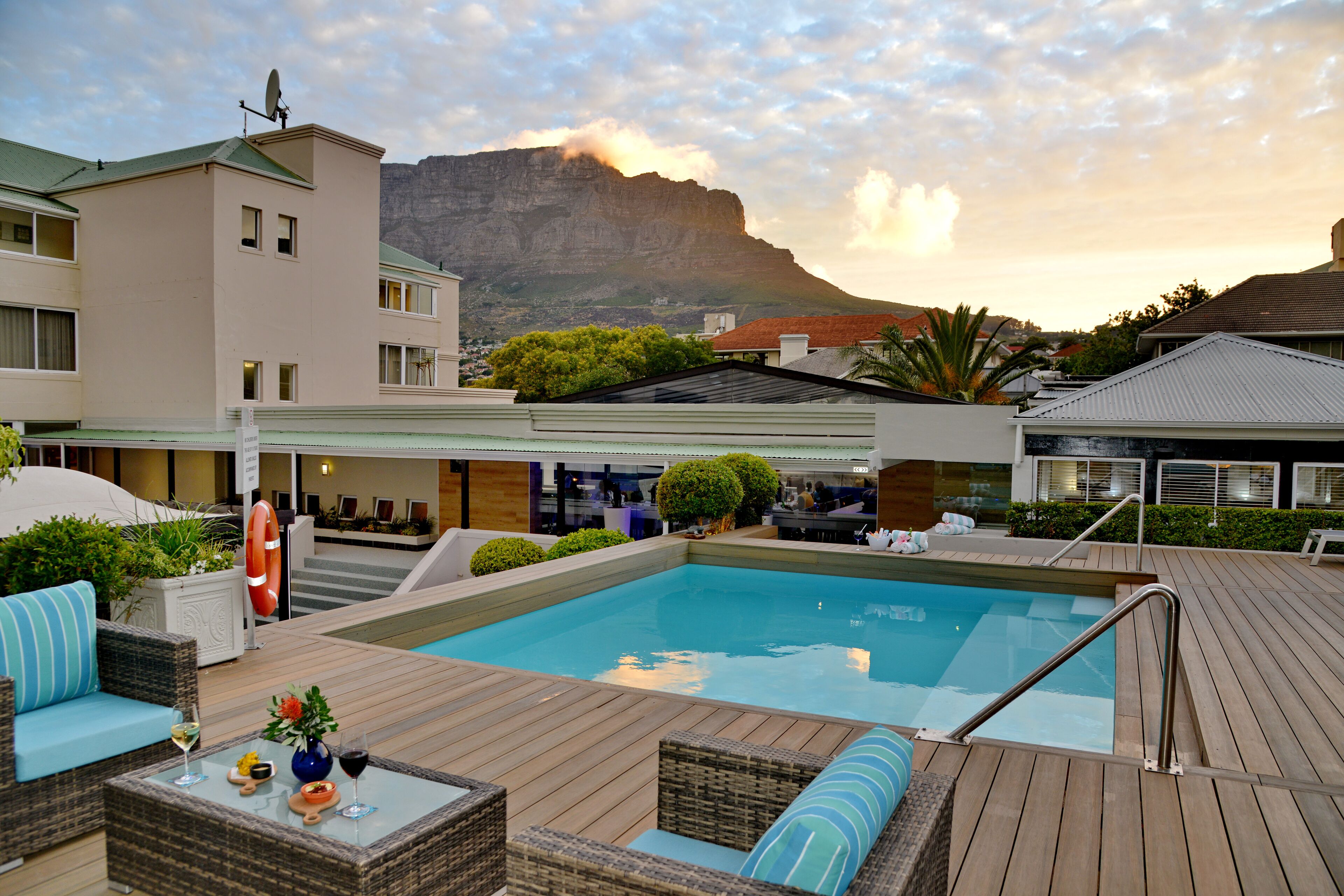 A pool area with a view of a mountain, outdoor seating, and a building with a flat roof.
