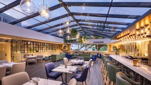Un restaurant moderne doté d’un plafond en verre, de planchers en bois et d’un espace bar.