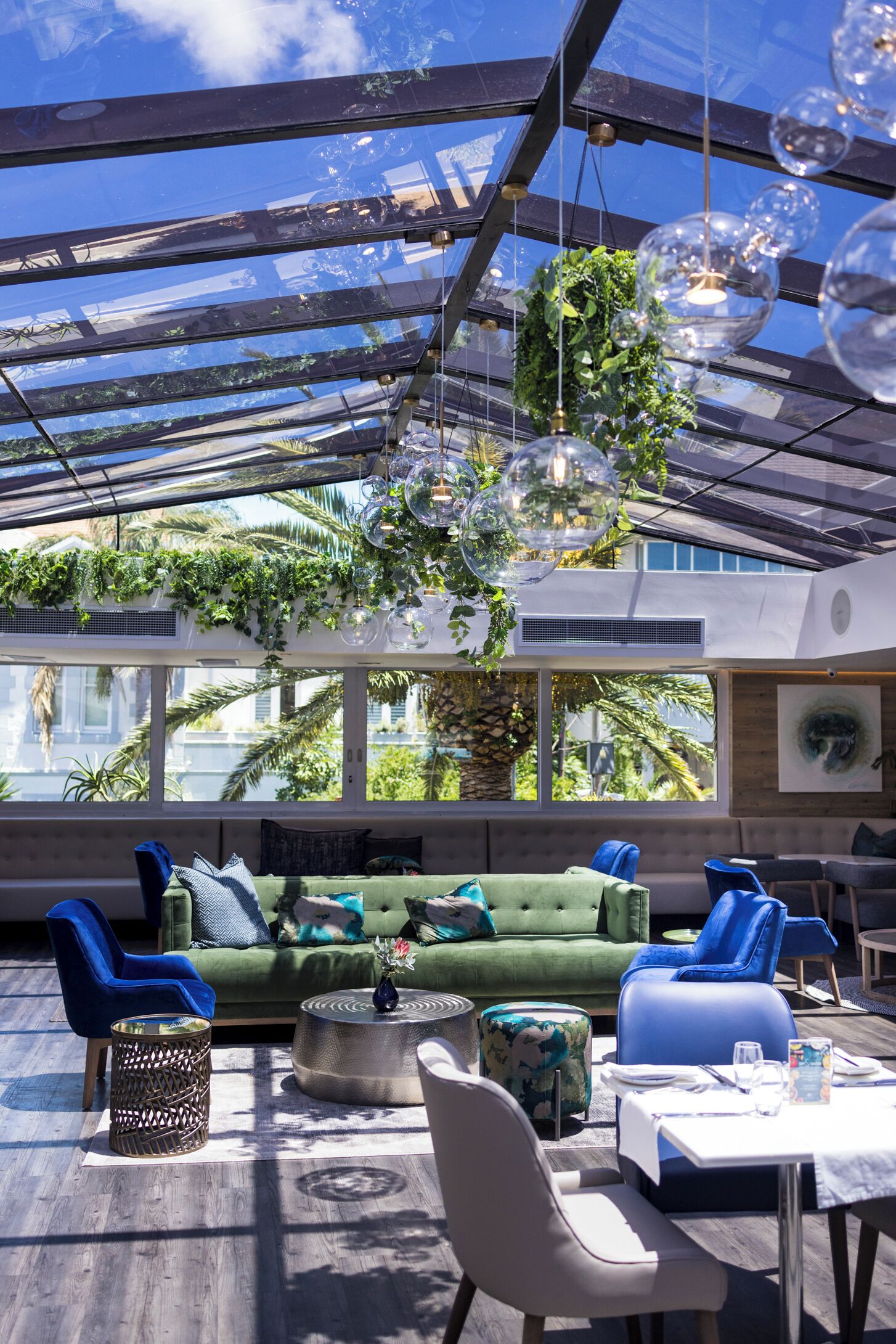 Un espace intérieur moderne doté d’un plafond en verre, de plantes vertes et de sièges confortables.
