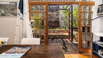 Une terrasse en bois avec un mur en pierre, une chaise blanche et une table sur laquelle se trouve un livre.