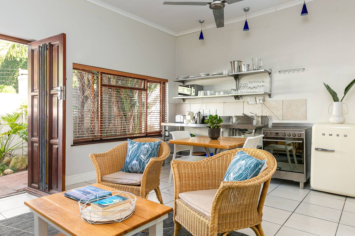 A kitchen with wicker furniture, a white refrigerator, and a dining table.