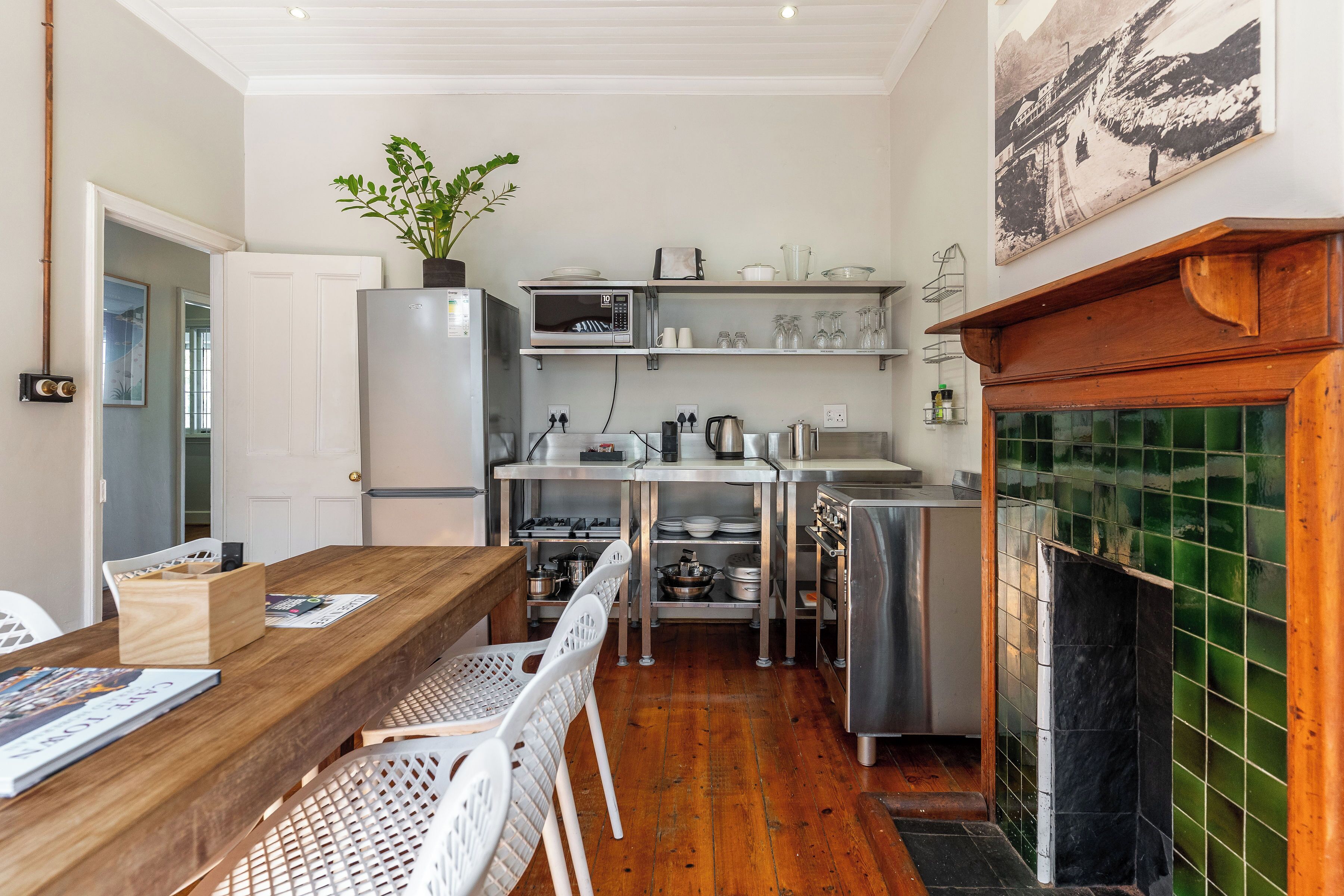 A compact kitchen with a wooden table, white chairs, a refrigerator, a microwave, and a stove.
