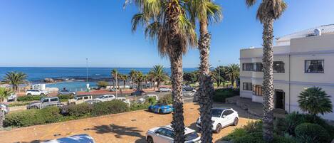 A coastal property with a parking area, palm trees, and a view of the sea.