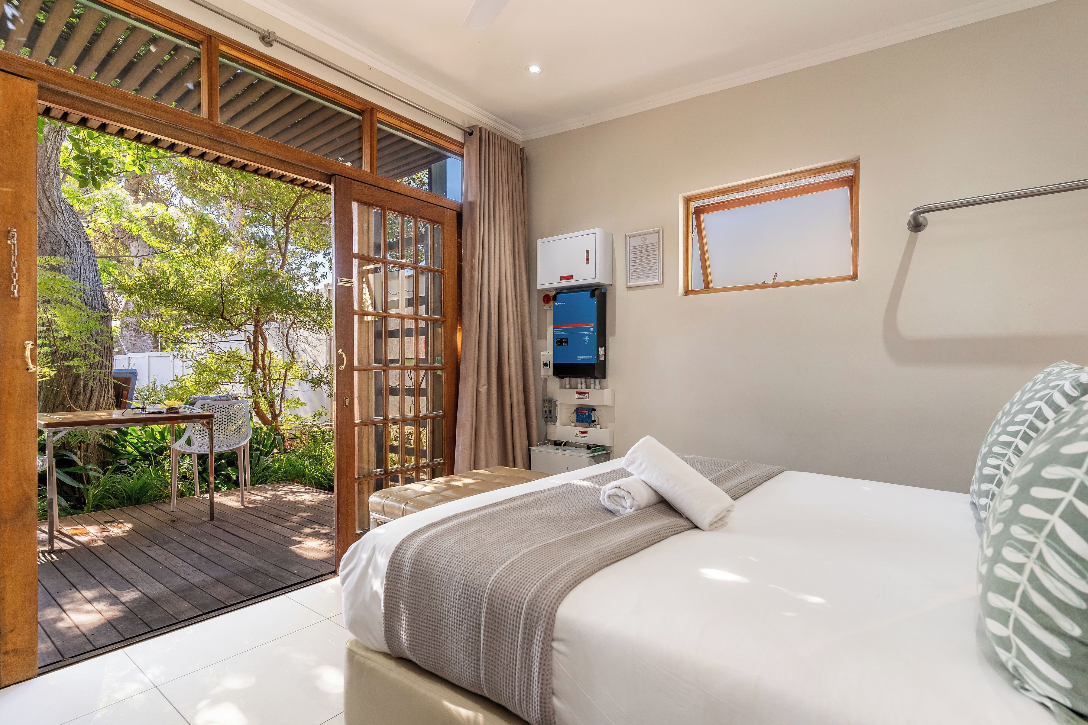 A bedroom with a bed, a desk, and a view of the outdoors.