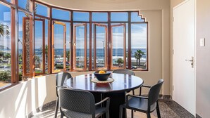 A corner room with a round table, four chairs, and a bowl with a lemon on it.