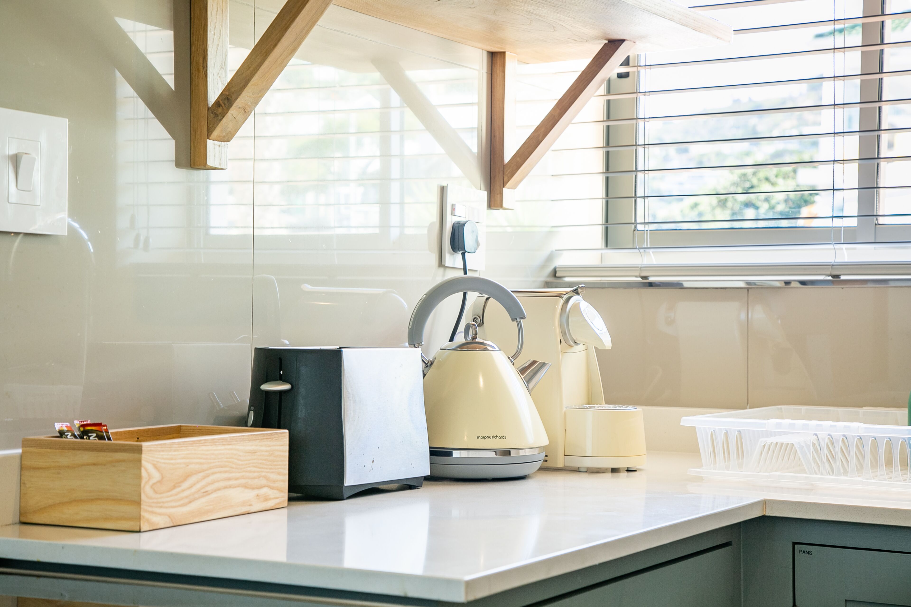 A kitchen with a wooden countertop, a kettle, a toaster, and a plastic container.