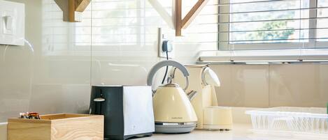 A kitchen with a wooden countertop, a kettle, a toaster, and a plastic container.